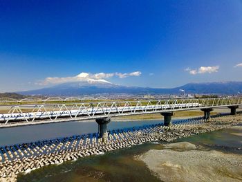 Bridge over sea against blue sky with mt. fuji and shinkansen