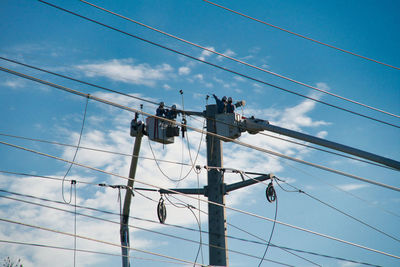 Low angle view of electricity pylon against blue sky