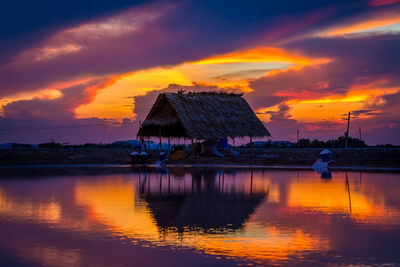 Scenic view of lake against dramatic sky during sunset