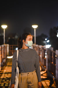 Woman wearing mask in city at night