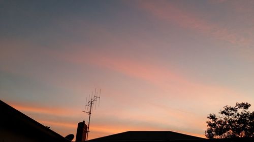 Low angle view of silhouette communications tower against sky during sunset