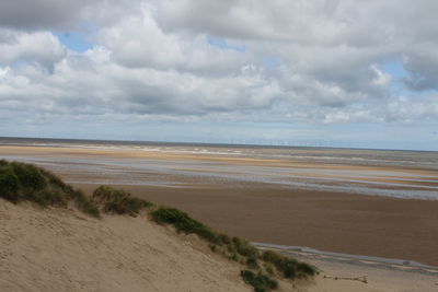 Scenic view of beach against cloudy sky