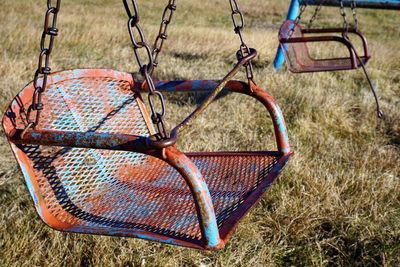 Old swing hanging at grassy playground on sunny day