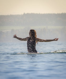 Woman splashing water in lake against sky