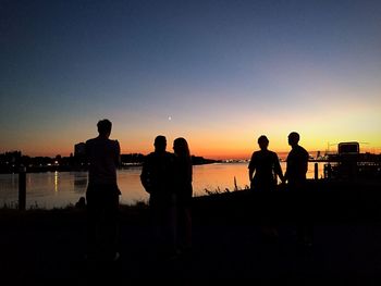 Silhouette people standing in city against clear sky during sunset