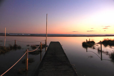 Pier over lake against sky during sunset