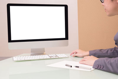 High angle view of businessman using computer while writing note at desk