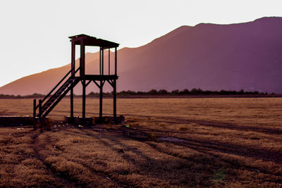 Lifeguard hut on field against sky during sunset