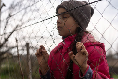 Portrait of woman standing against chainlink fence