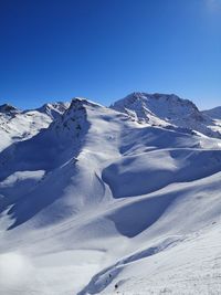 Scenic view of snowcapped mountains against clear blue sky