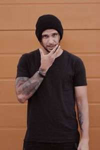 Portrait of young man standing against wall