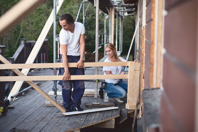 Full length of couple working on porch of house being renovated