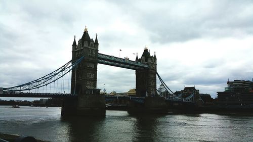 Low angle view of bridge over river against cloudy sky