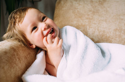 Cute baby in a big white towel. holds fingers in the mouth.