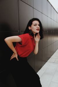 Young woman standing against wall