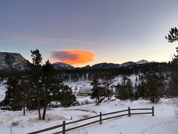 Orange lenticular cloud hanging over a mountain at sunset in wintertime