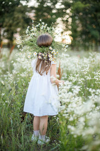 Midsection of woman standing by flowering plants on field