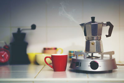 Close-up of cup nu coffee pot
