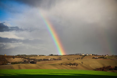 Scenic view of rainbow over field against sky