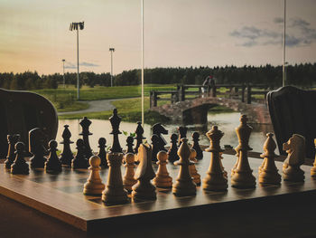 People relaxing on chess board against sky