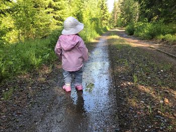 Rear view of girl walking in puddle