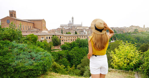 Panorama with young woman enjoying scenic view from tuscan hills in siena, tuscany, italy.