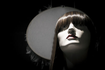 Close-up portrait of woman wearing hat against black background