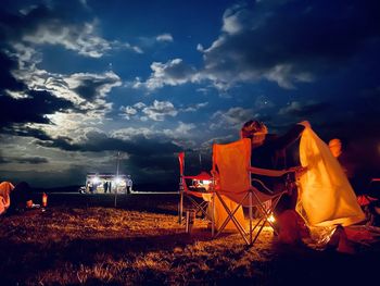 Chairs on field against sky at night