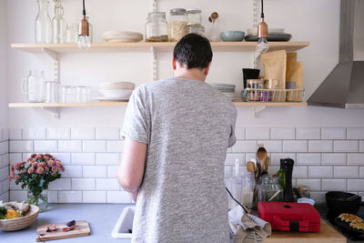 Rear view of man preparing food at kitchen counter