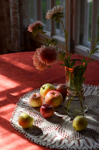 Appples and flowers in vase on table. 