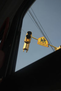 Low angle view of road signal seen through window against sky
