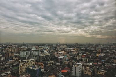 Aerial view of city against cloudy sky