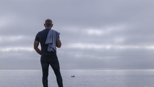 Rear view of adult man against cloudy sky and sea