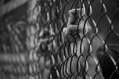 Cropped hand on chainlink fence