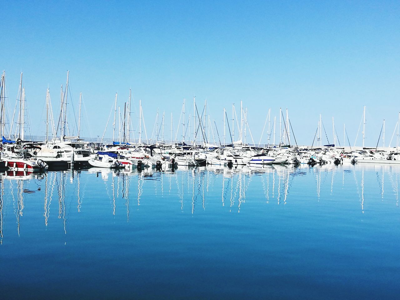 nautical vessel, water, mode of transportation, sailboat, transportation, reflection, sky, moored, waterfront, clear sky, pole, no people, copy space, mast, sea, nature, harbor, blue, day, yacht, marina, port, anchored