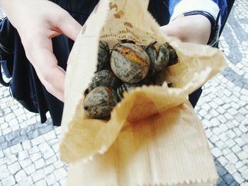 Person showing roasted chestnut in paper bag
