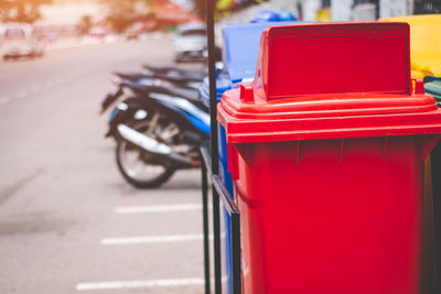 Red garbage can by road