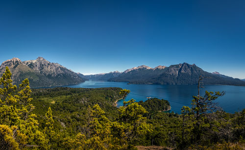 Scenic view of sea and mountains against clear blue sky