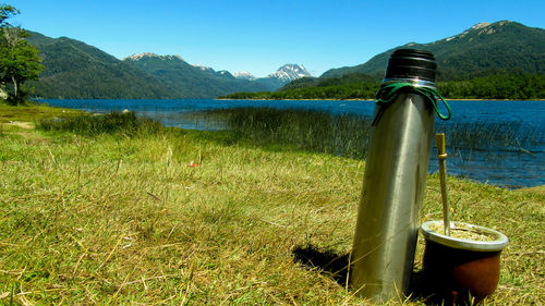 Travel mug by lake on field