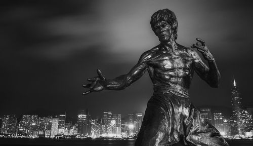 Statue against sky in city at night