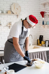 Midsection of woman standing on table in kitchen