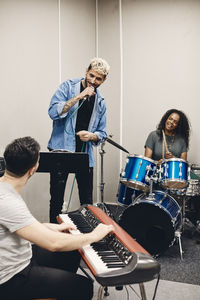 Young man singing while rehearsing with male and female friends in classroom