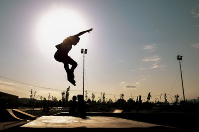 Silhouette man skateboarding on skateboard against sky