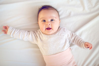 Portrait of cute baby lying on bed at home