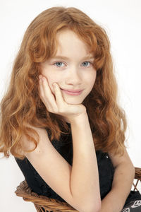 Portrait of girl sitting on chair against white background