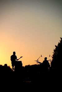 Silhouette people standing against clear sky during sunset