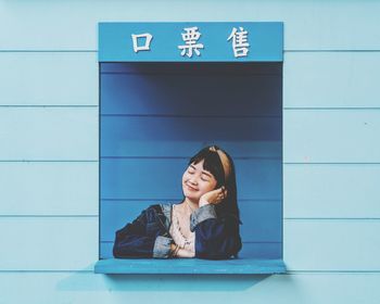 Portrait of a smiling young woman against wall