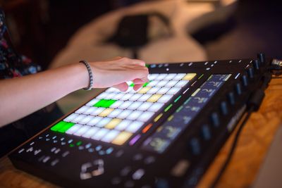 Cropped hand of dj playing music on sound mixer in nightclub