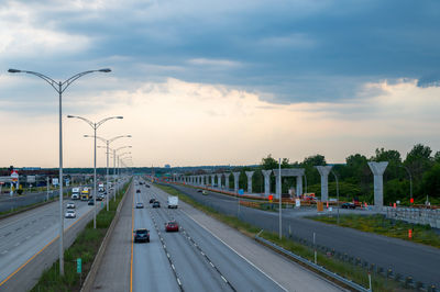 Highway in city against sky during sunset