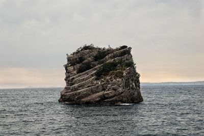 Rock formation in sea against sky